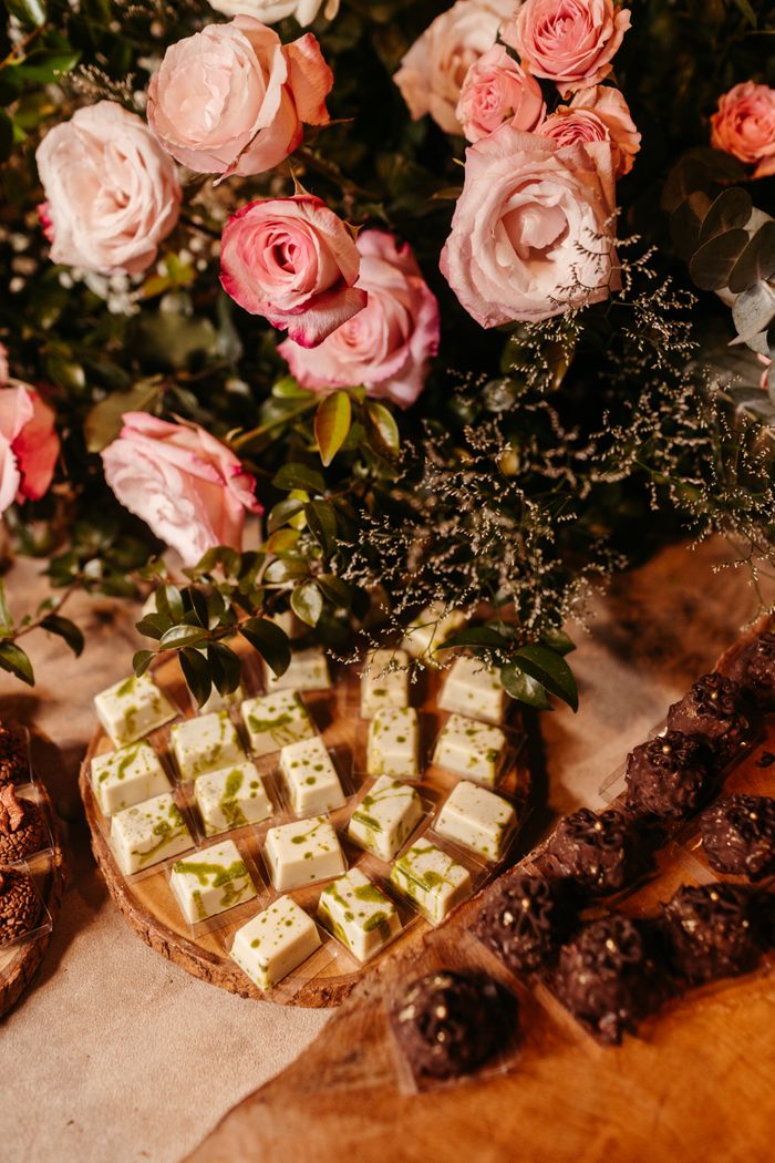 Home An elegant display of assorted desserts with roses on wooden trays for a banquet.
