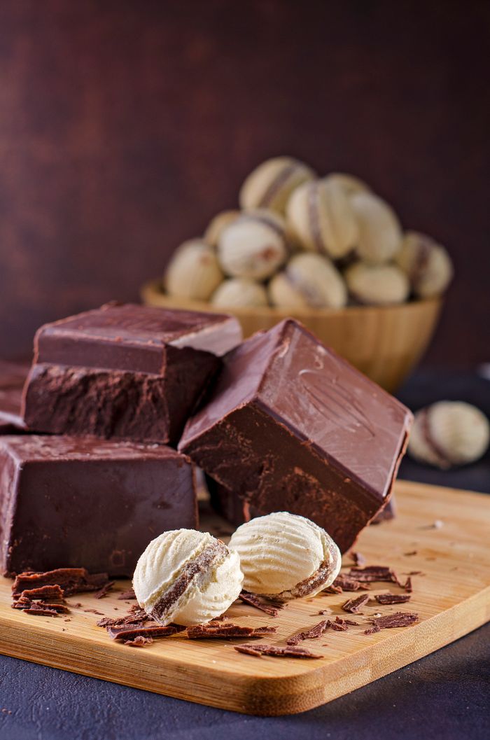 Home Close-up of creamy dark and white chocolate blocks on wooden board with truffles. Perfect for dessert inspiration.