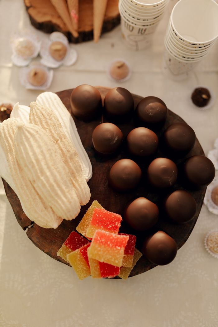Home A delicious assortment of chocolates, wafers, and jellies on a wooden platter, perfect for dessert displays.