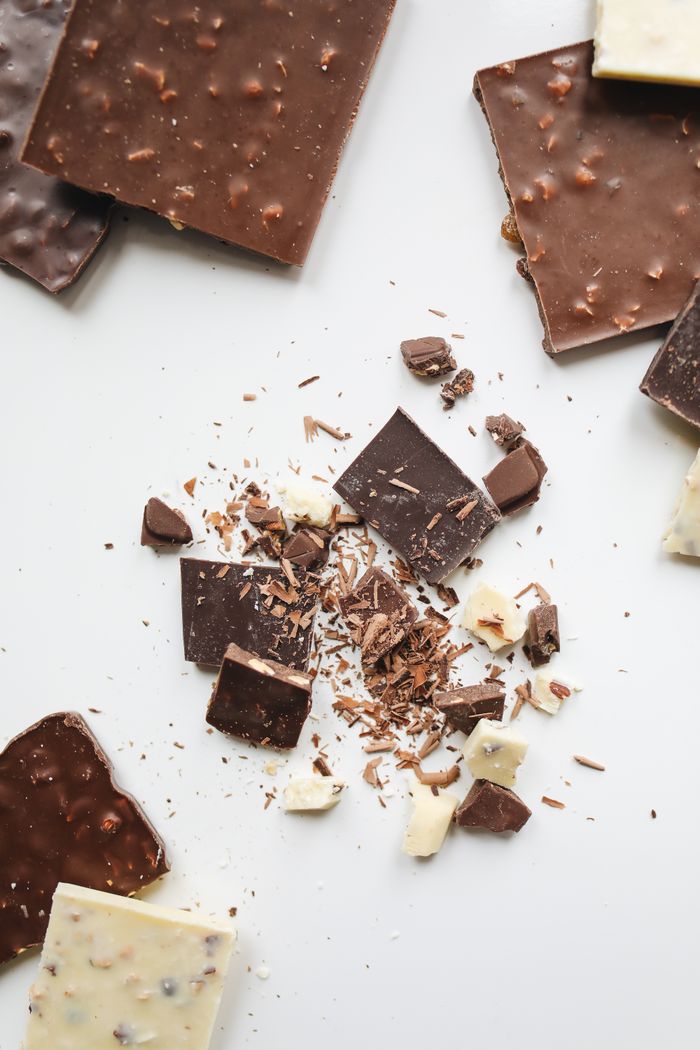 Home Delicious milk and dark chocolate bars with shavings spread on a white surface.
