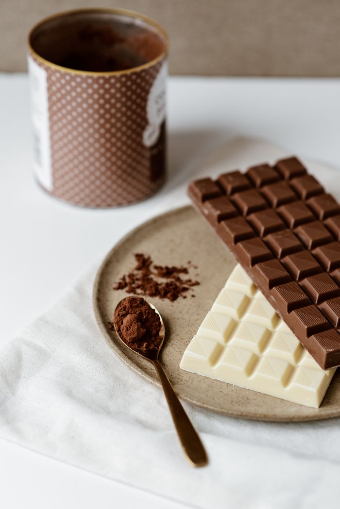 Home High angle of various chocolate and spoon with cocoa powder on modern ceramic plate